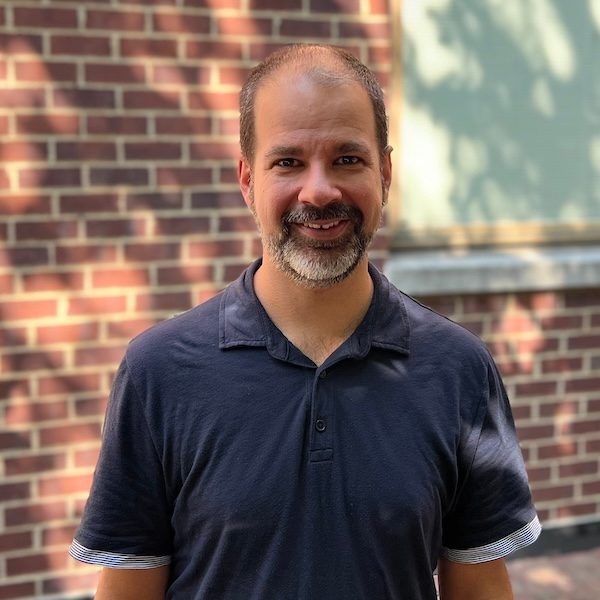 Outdoor headshot of researcher Sanmay Das in a dark blue polo shirt.